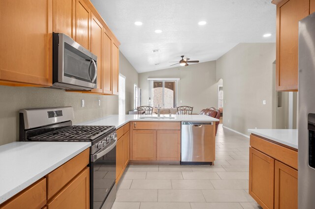 kitchen with ceiling fan, vaulted ceiling, light tile patterned floors, sink, and stainless steel appliances