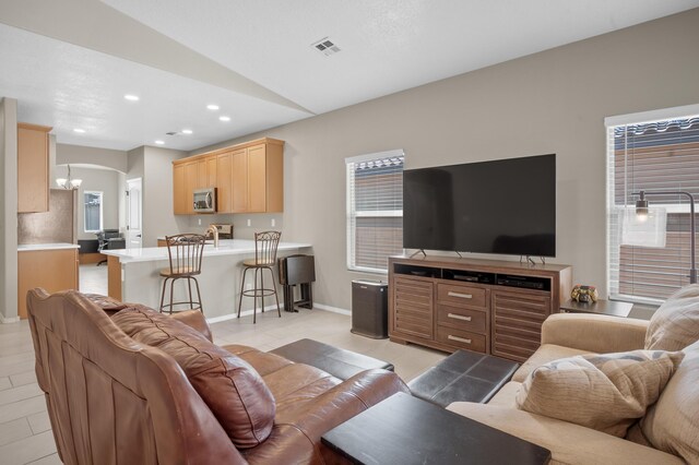 tiled living room featuring an inviting chandelier and lofted ceiling