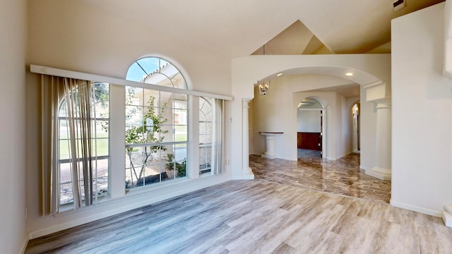 spare room with high vaulted ceiling, hardwood / wood-style flooring, and a wealth of natural light