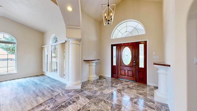 entrance foyer with a notable chandelier, decorative columns, and tile patterned floors