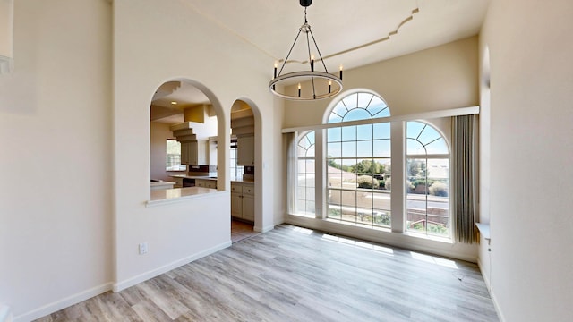 interior space with a notable chandelier, light wood-type flooring, and a high ceiling