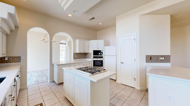 kitchen with decorative backsplash, white cabinetry, appliances with stainless steel finishes, a center island, and light hardwood / wood-style floors