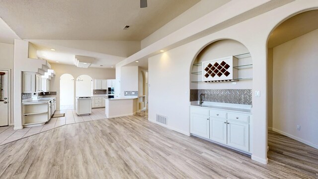 unfurnished living room featuring lofted ceiling, sink, and light tile patterned floors