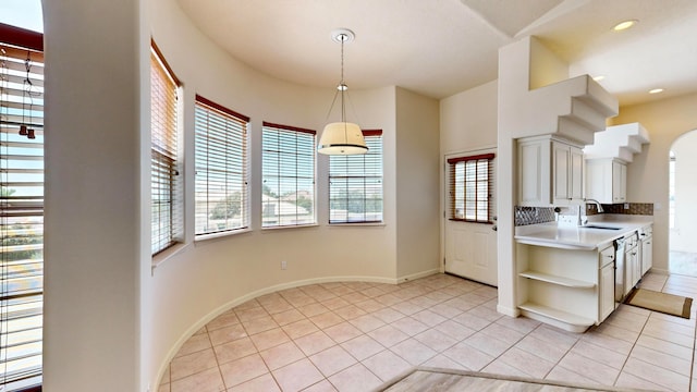 kitchen featuring sink, tasteful backsplash, decorative light fixtures, and light tile patterned floors