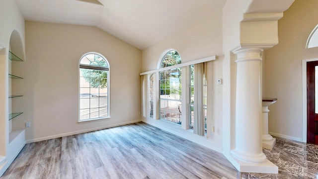 unfurnished room with decorative columns, lofted ceiling, and light hardwood / wood-style floors