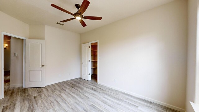 unfurnished bedroom with a spacious closet, ceiling fan, light hardwood / wood-style floors, and a closet