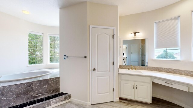 bathroom featuring vanity, hardwood / wood-style flooring, and tiled bath