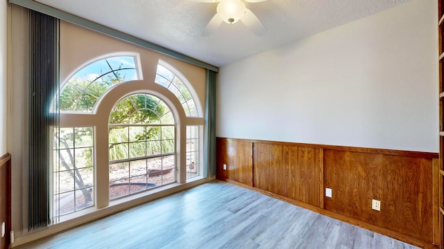 doorway to outside with ceiling fan, light hardwood / wood-style flooring, wood walls, and plenty of natural light