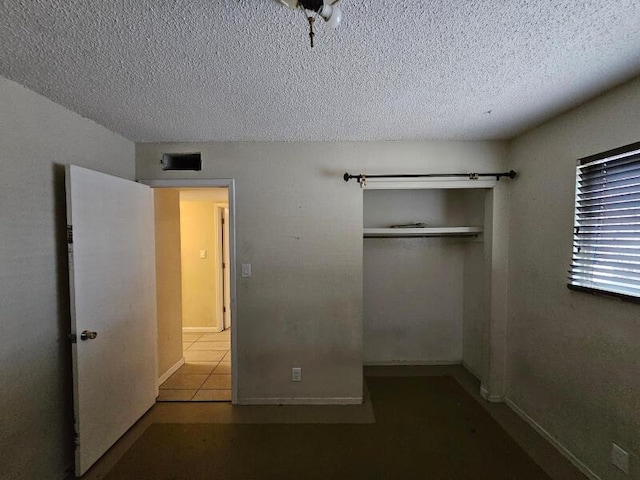 unfurnished bedroom featuring visible vents, baseboards, tile patterned flooring, a closet, and a textured ceiling