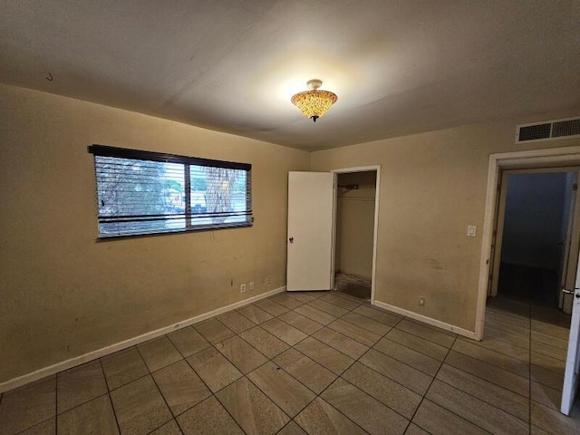 unfurnished bedroom featuring tile patterned floors, visible vents, baseboards, and a closet