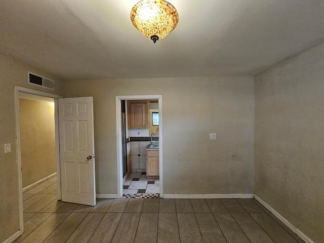 empty room with a sink, visible vents, and baseboards