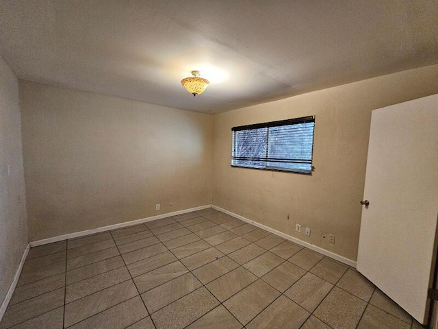 empty room with tile patterned flooring and baseboards