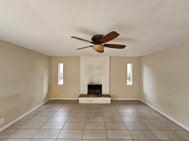 unfurnished living room with light tile patterned floors, a brick fireplace, a textured ceiling, and a ceiling fan