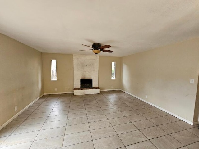 unfurnished living room with a brick fireplace, light tile patterned floors, baseboards, and ceiling fan