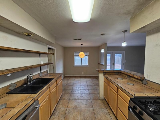 kitchen with tile countertops, visible vents, a sink, a textured ceiling, and stainless steel dishwasher