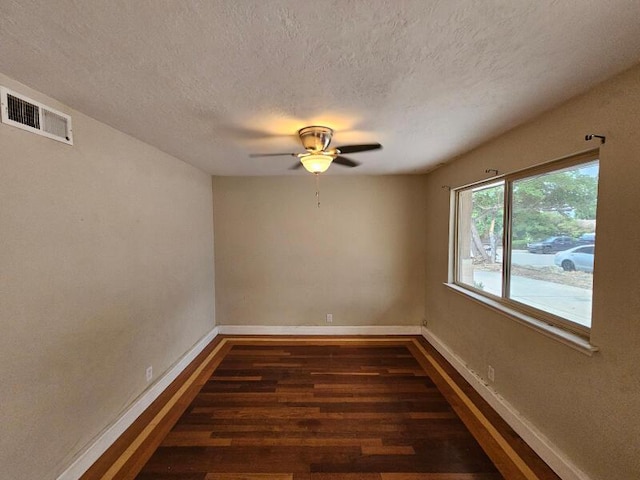 unfurnished room with visible vents, baseboards, a textured ceiling, and wood finished floors