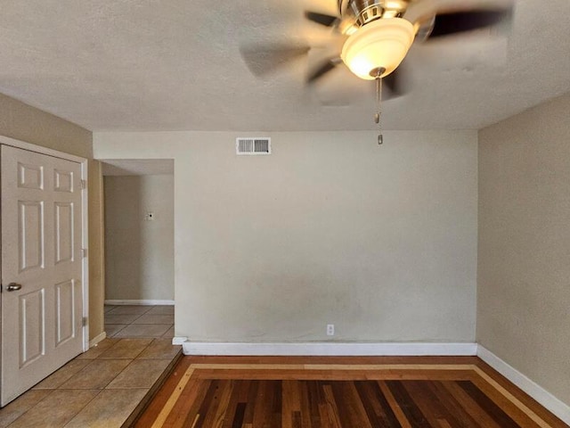 tiled empty room featuring visible vents, ceiling fan, and baseboards