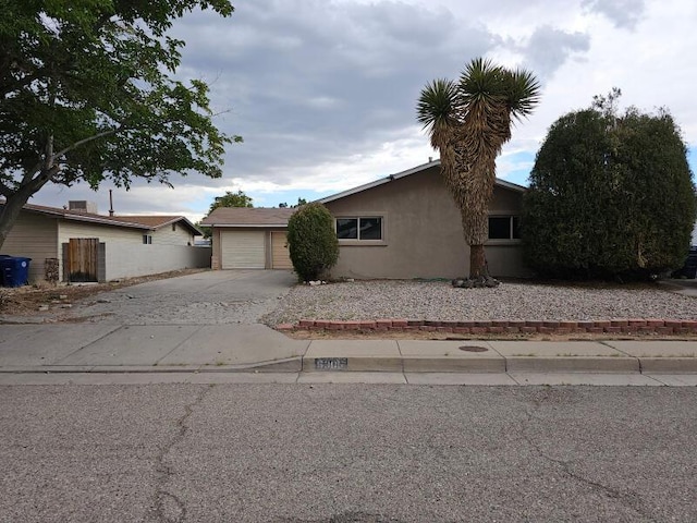 view of front of house with stucco siding, driveway, and fence