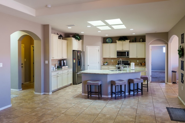 kitchen with sink, backsplash, appliances with stainless steel finishes, and light tile patterned floors