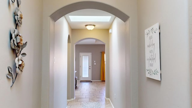 corridor featuring light tile patterned flooring and a skylight