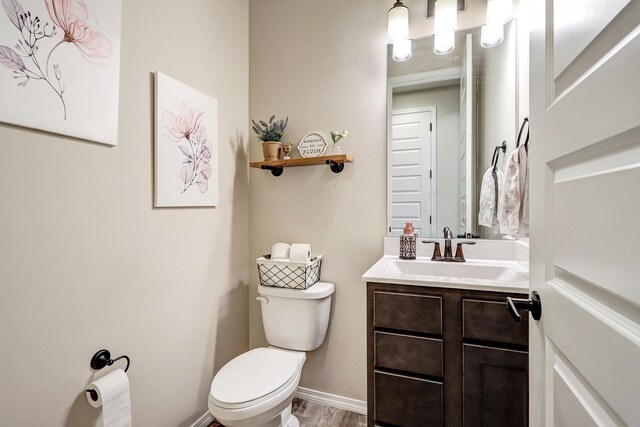 bathroom featuring toilet, hardwood / wood-style flooring, and vanity