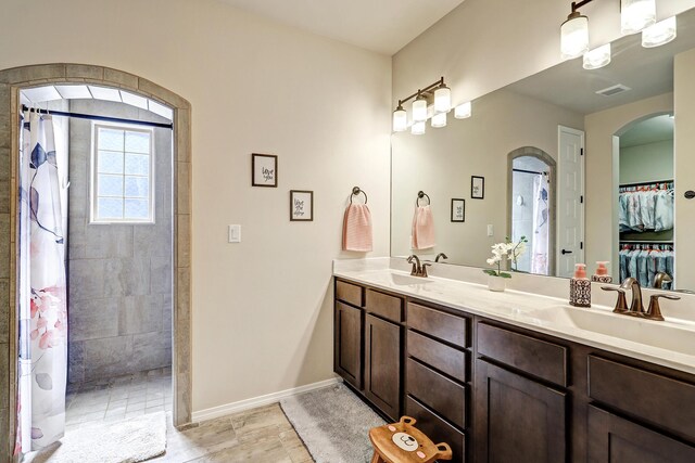 bathroom with a tile shower and vanity