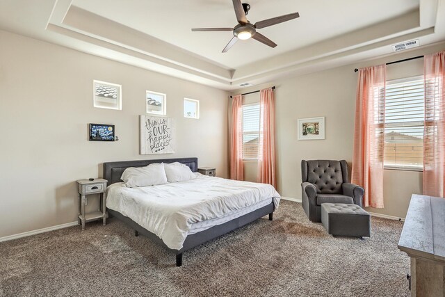 carpeted bedroom featuring a tray ceiling and ceiling fan