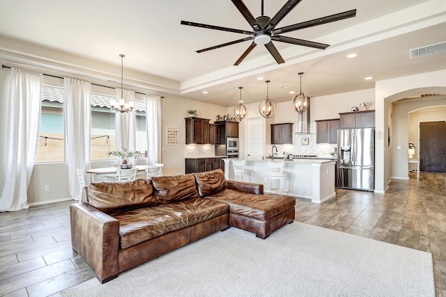 living room featuring ceiling fan with notable chandelier and sink