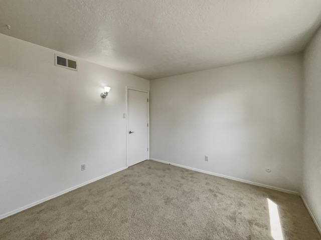 unfurnished room featuring baseboards, carpet, visible vents, and a textured ceiling