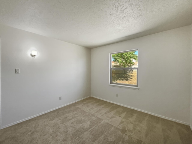 carpeted empty room with a textured ceiling and baseboards