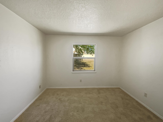 carpeted spare room with a textured ceiling and baseboards