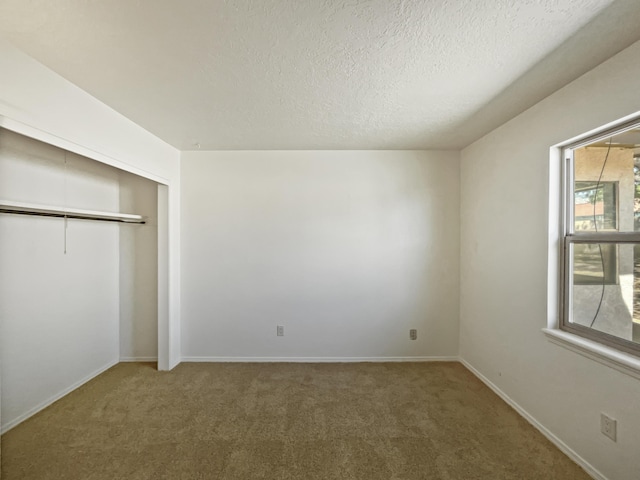 unfurnished bedroom featuring carpet floors, a closet, a textured ceiling, and baseboards