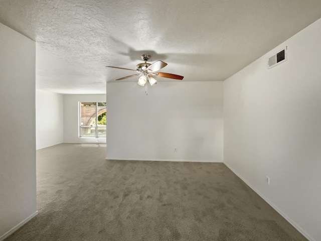 spare room with carpet floors, visible vents, ceiling fan, a textured ceiling, and baseboards