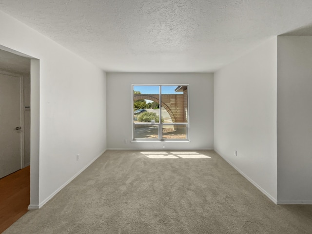 unfurnished room with carpet, a textured ceiling, and baseboards