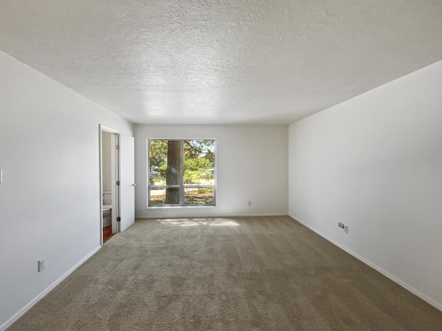 spare room featuring carpet flooring, a textured ceiling, and baseboards