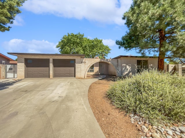 ranch-style home with concrete driveway, brick siding, fence, and a gate