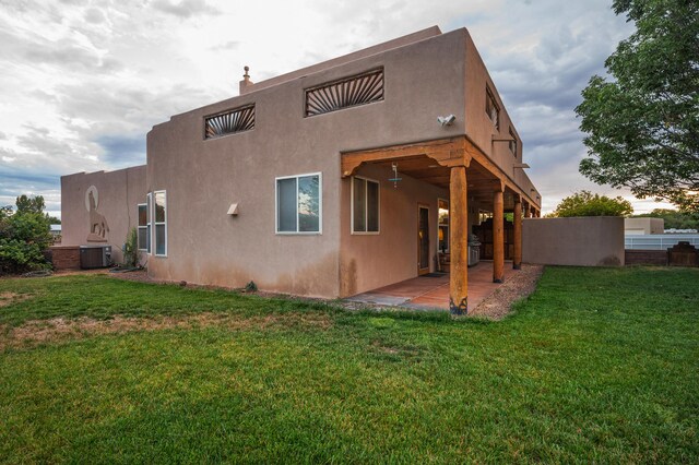 rear view of house featuring a patio, central AC, and a lawn