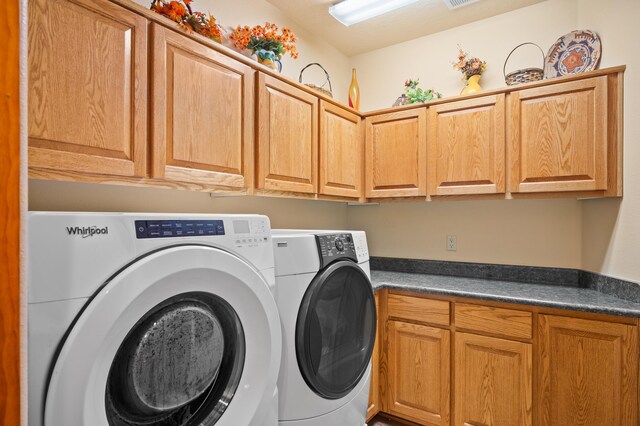 clothes washing area featuring washing machine and clothes dryer and cabinets