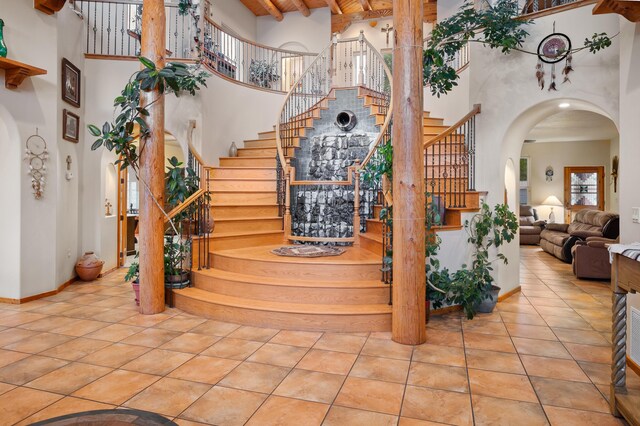 stairway featuring beam ceiling, a high ceiling, and tile patterned flooring