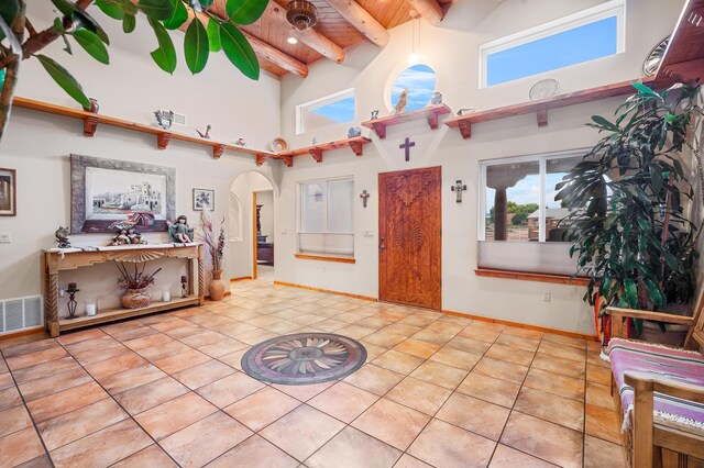 tiled entryway with beamed ceiling, wooden ceiling, and a high ceiling