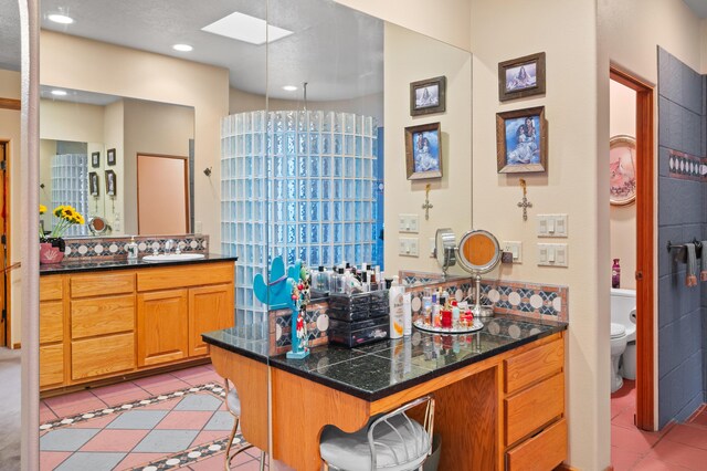 bathroom with a skylight, tile patterned floors, toilet, and vanity