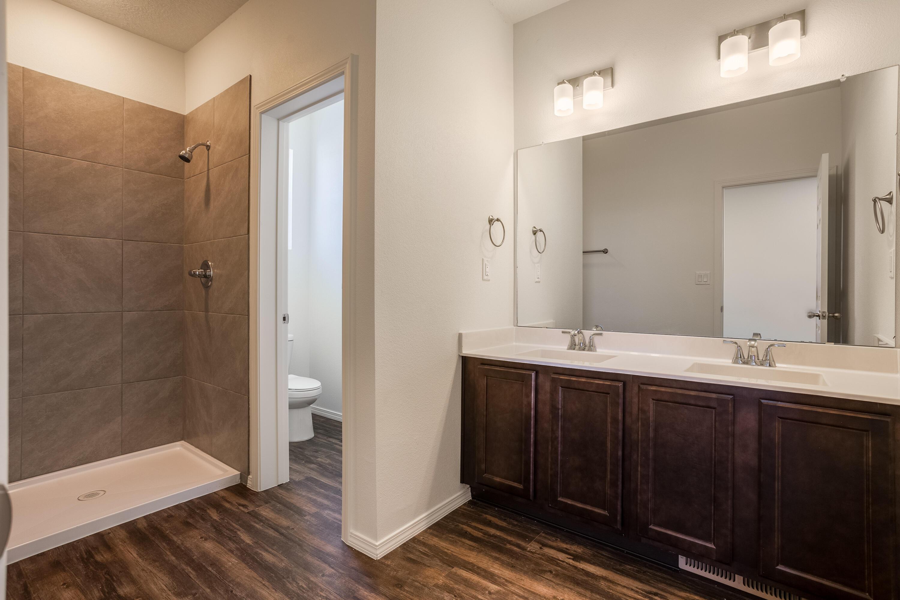 bathroom with hardwood / wood-style floors, vanity, a tile shower, and toilet