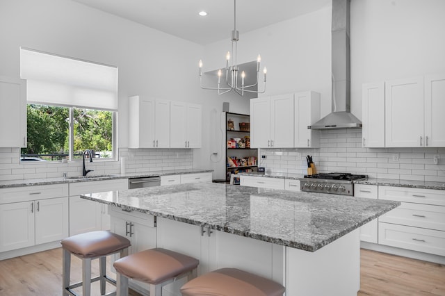 kitchen featuring wall chimney exhaust hood, a sink, and white cabinetry