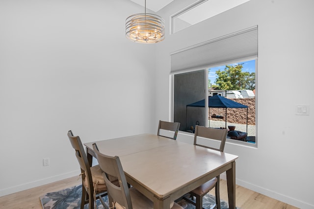 dining area with light wood-style floors, baseboards, and a notable chandelier