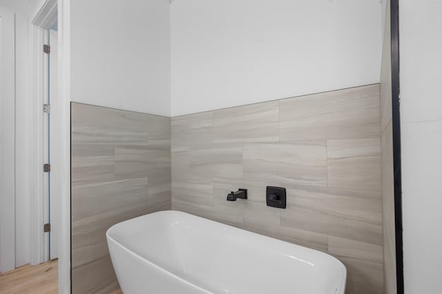 full bath featuring a freestanding tub and tile walls