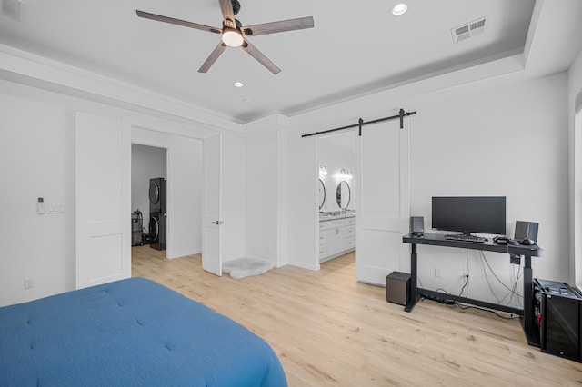 bedroom with a barn door, light wood-style flooring, visible vents, and recessed lighting