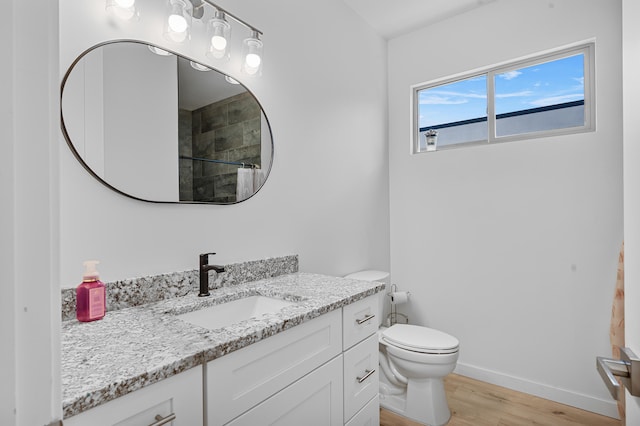 bathroom featuring baseboards, toilet, wood finished floors, walk in shower, and vanity