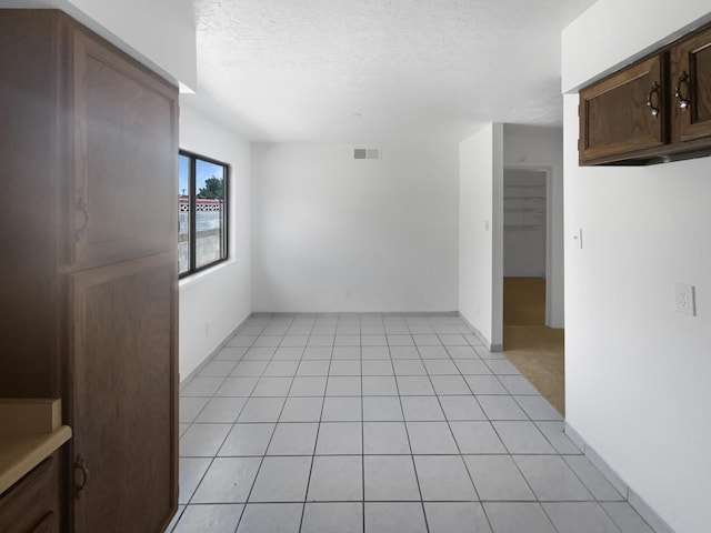 unfurnished room featuring light tile patterned floors and a textured ceiling