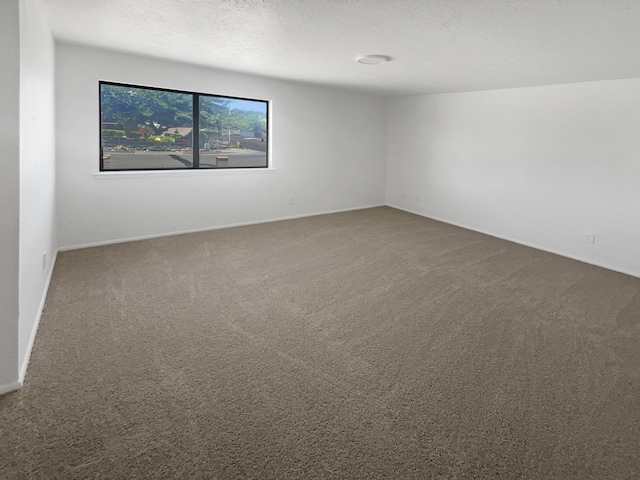 carpeted empty room featuring a textured ceiling