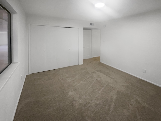 unfurnished bedroom with visible vents, baseboards, carpet flooring, and a closet
